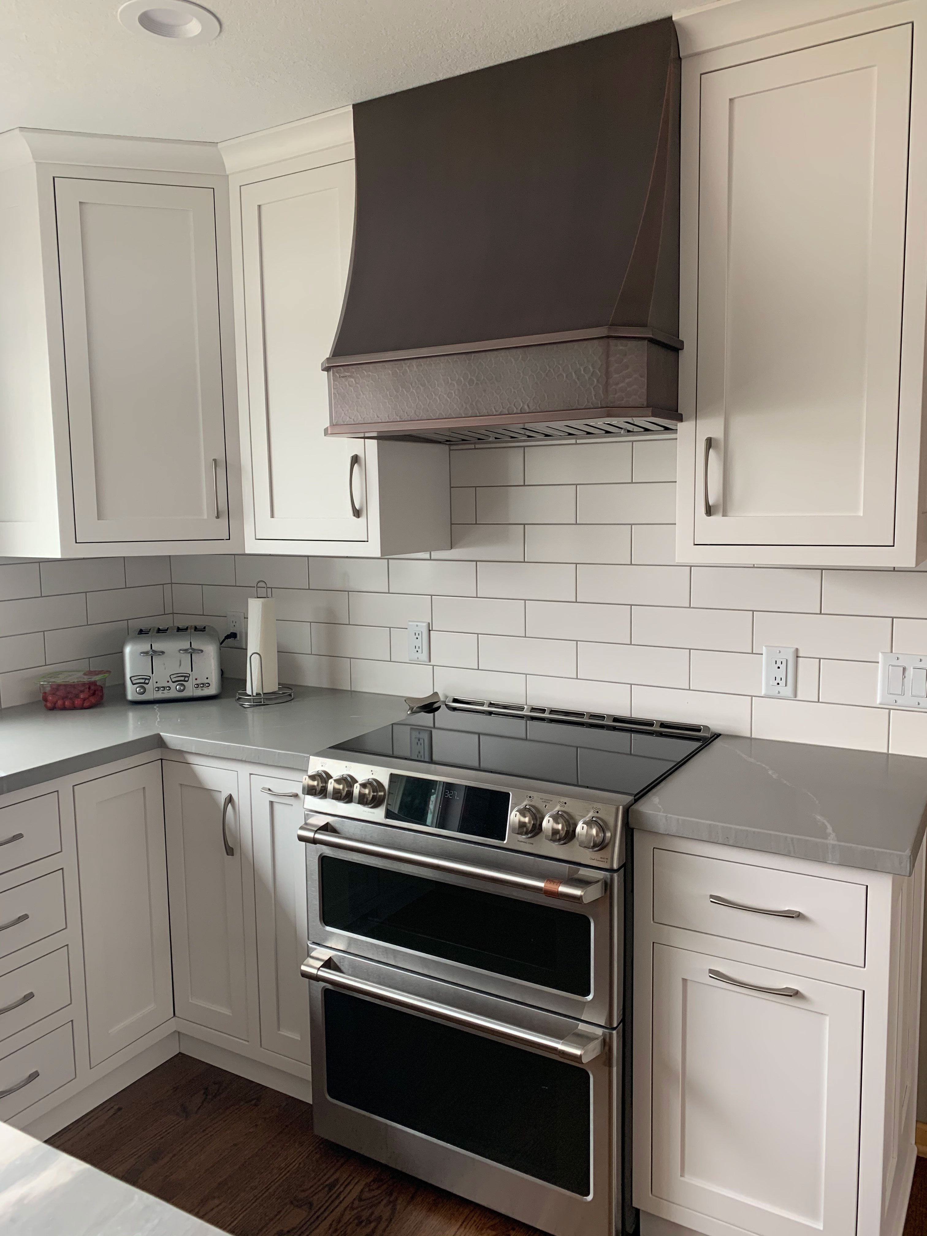 Inspiring kitchen design idea with the perfect range hood, white kitchen cabinets, quartz kitchen countertops, marble backsplash