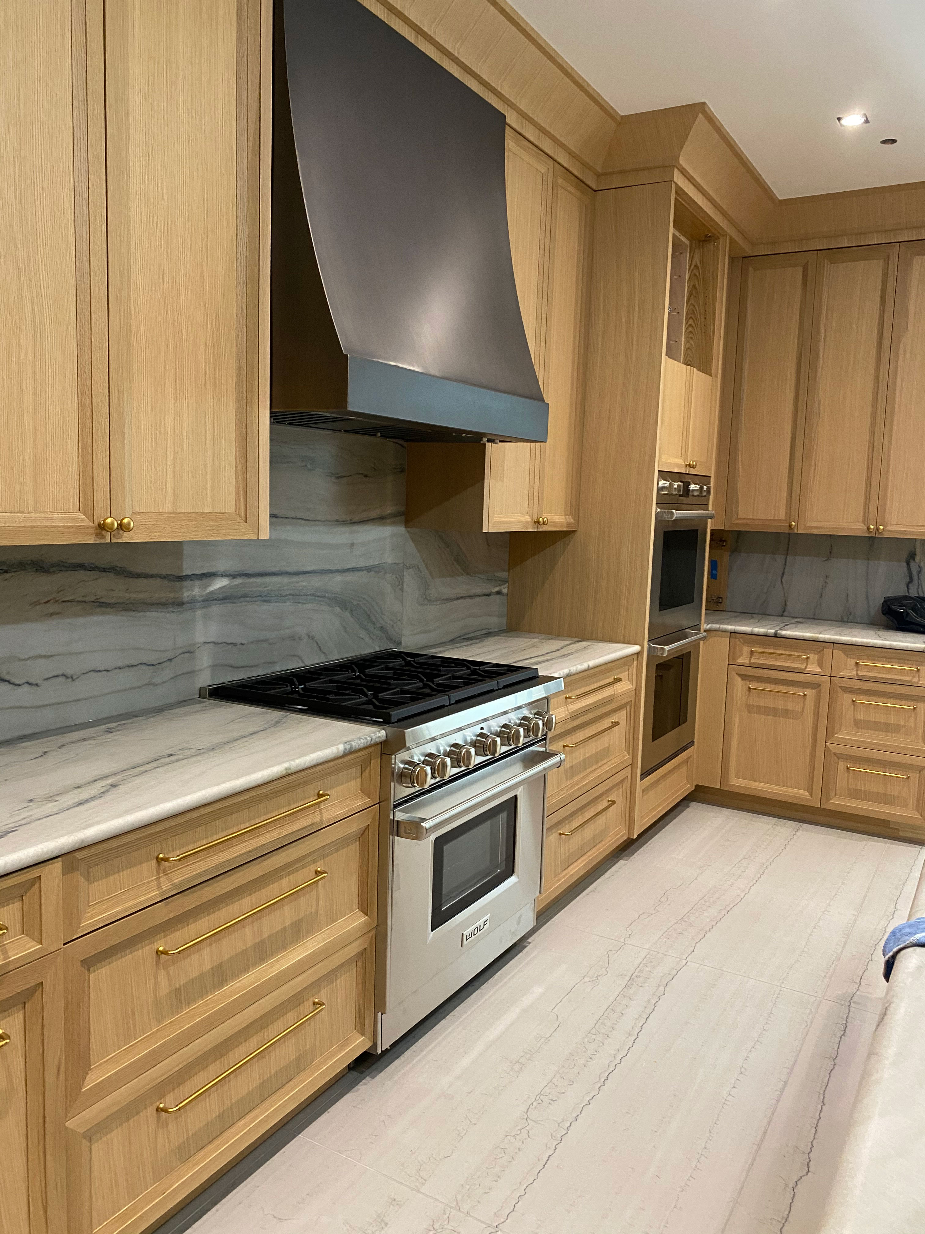 Kitchen design idea with clever range hood , brown kitchen cabinets, marble kitchen countertops, marble backsplash