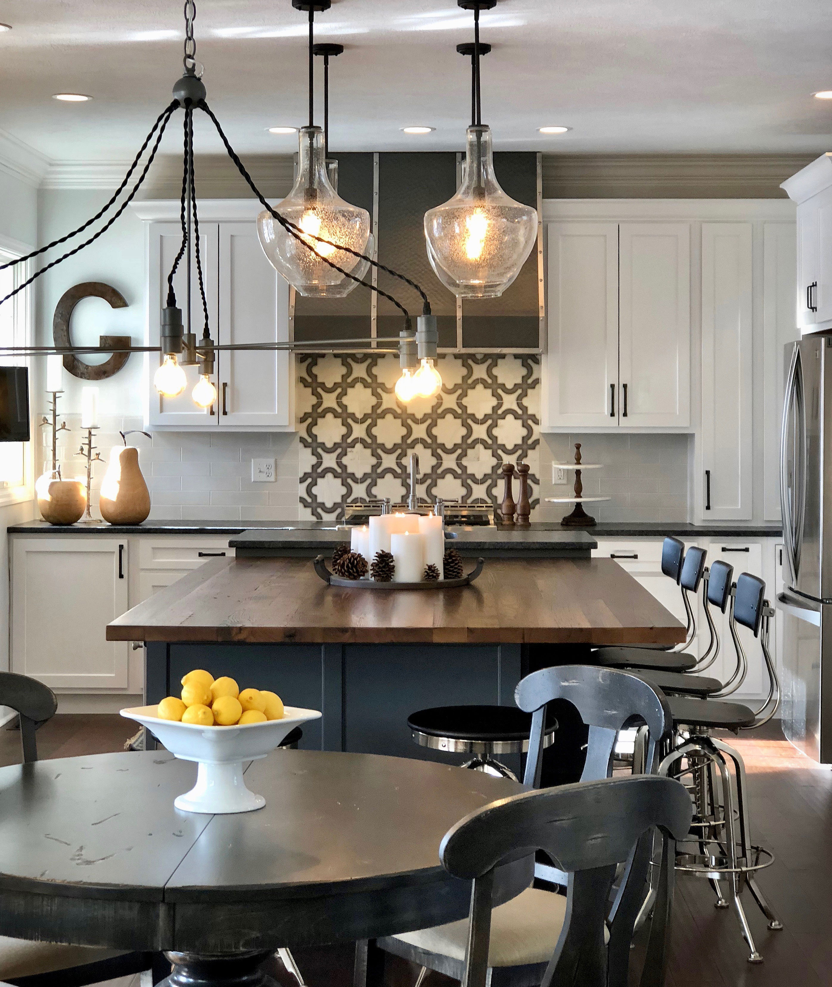 Kicthen design idea featuring beautiful table, white kitchen cabinets, black countertops and brick backsplash