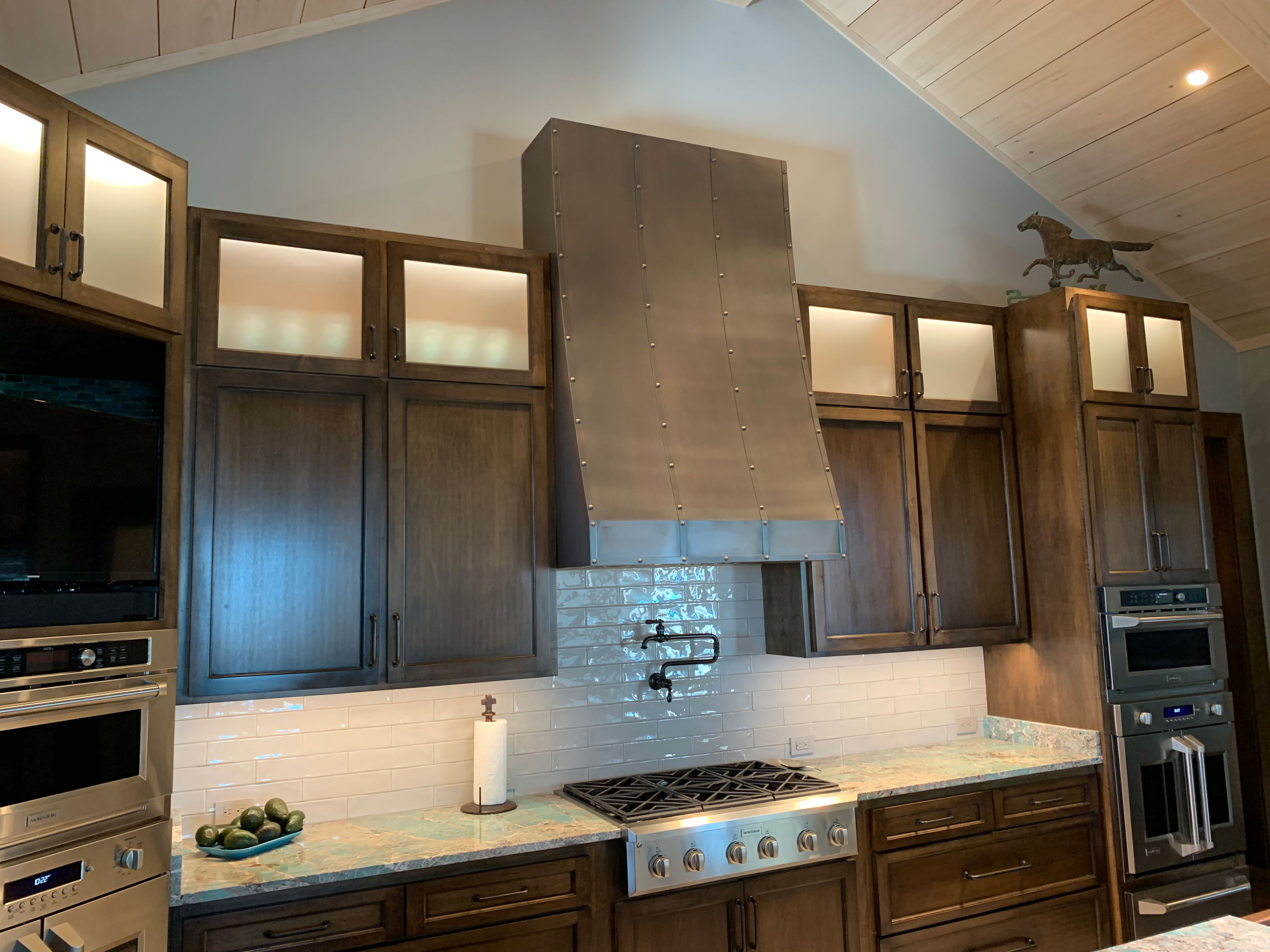 Kitchen design idea with copper range hood with brown cabinets, marble countertops, stylish brick backsplash