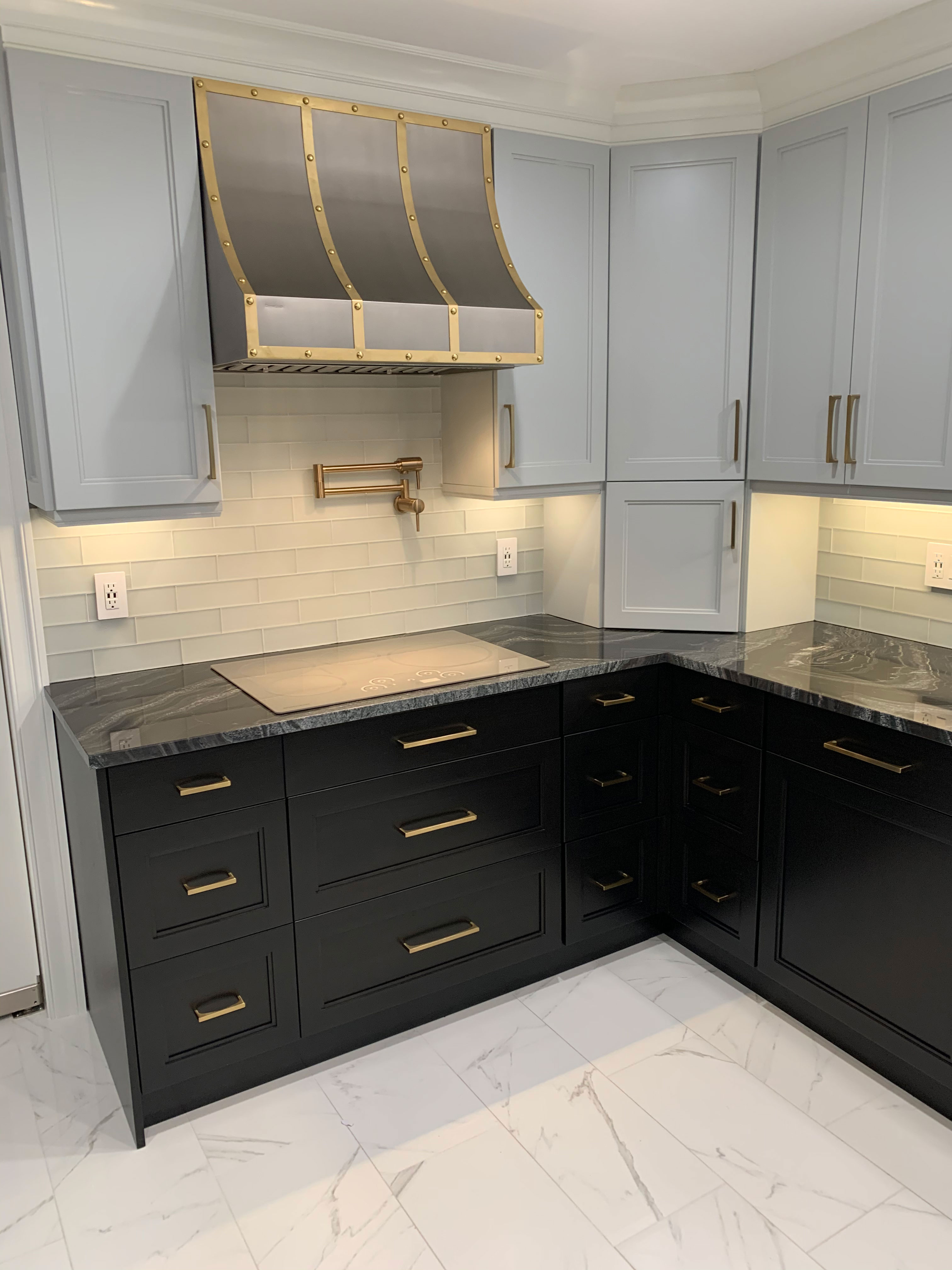 Classic kitchen design featuring black kitchen cabinets and countertops with a brick backsplash, complemented by a stylish range hood