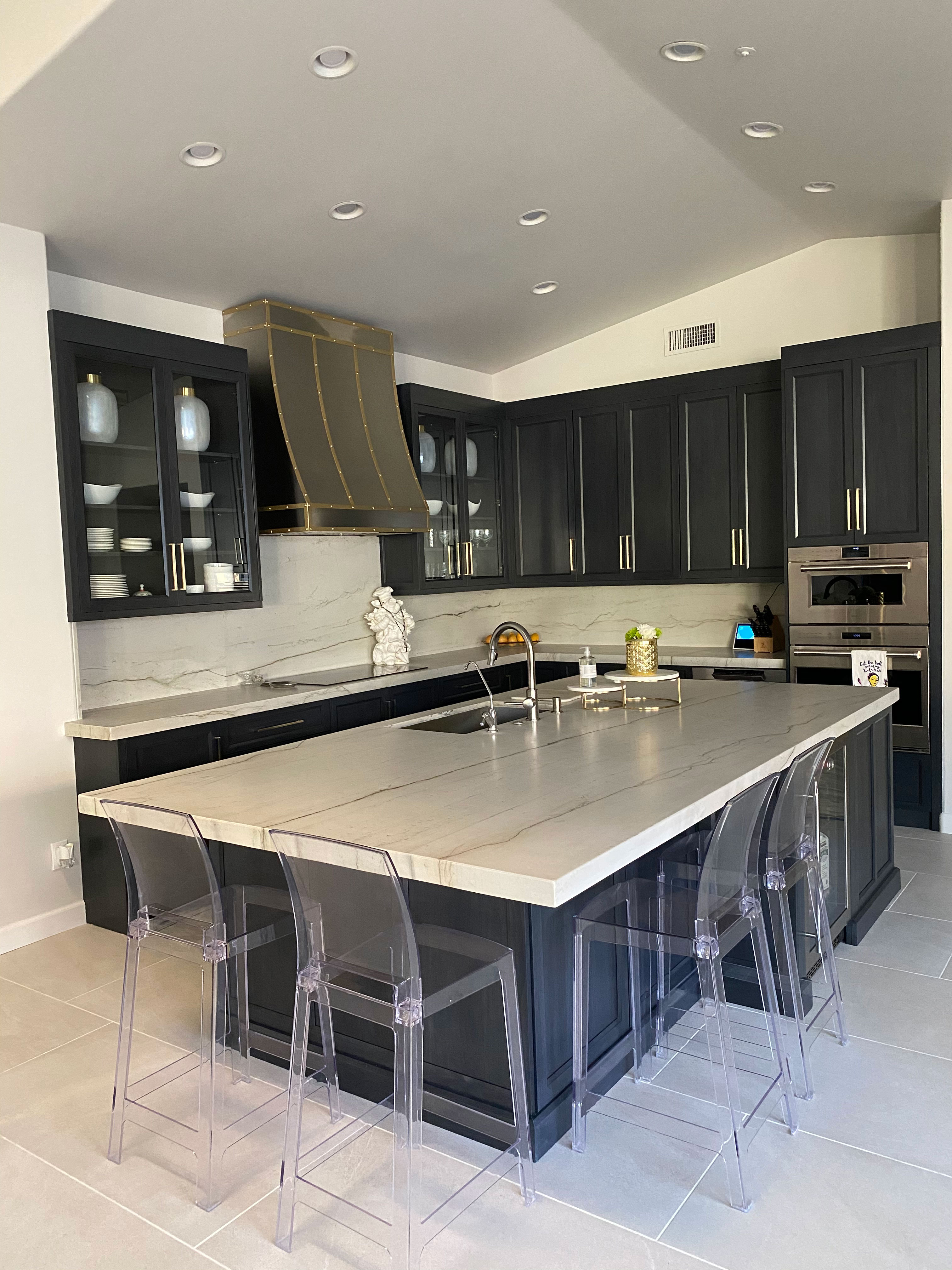 A contemporary kitchen remodeling with sleek black kitchen cabinets and marble kitchen countertops, complemented by a stunning marble backsplash