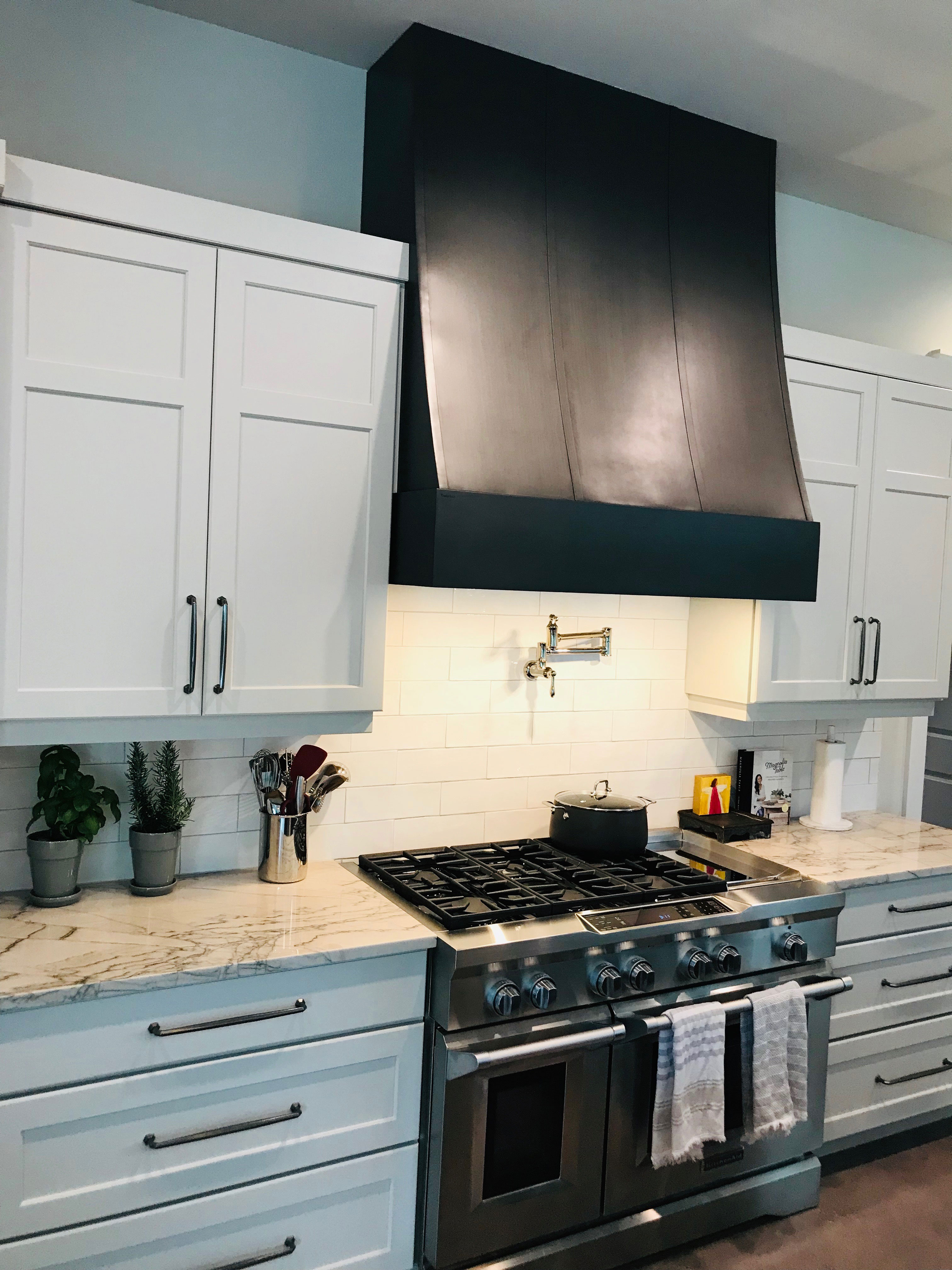 Fabulous contemporary kitchen remodel with white kitchen cabinets, marble countertops, sleek range hood, accentuated by a striking brick backsplash