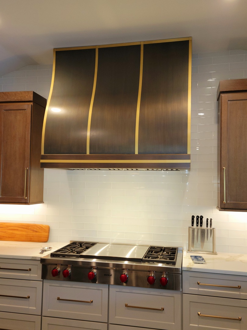 Kitchen design with range hood by pairing brown cabinets with elegant marble countertops and captivating brick backsplash