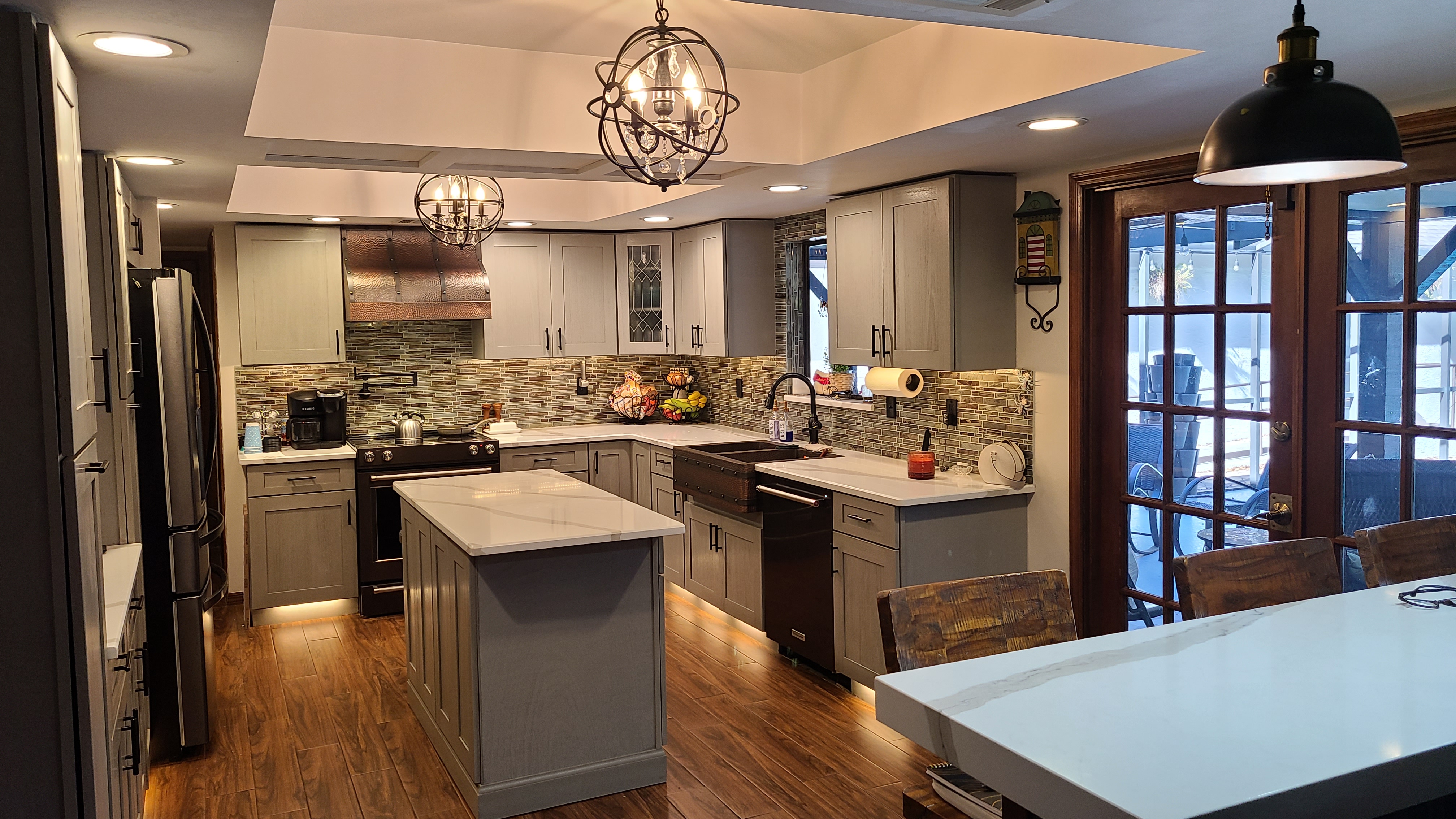 Copper sleek range hood into french-inspired kitchen design with brown kitchen cabinets,white kitchen countertops charming brick backsplash