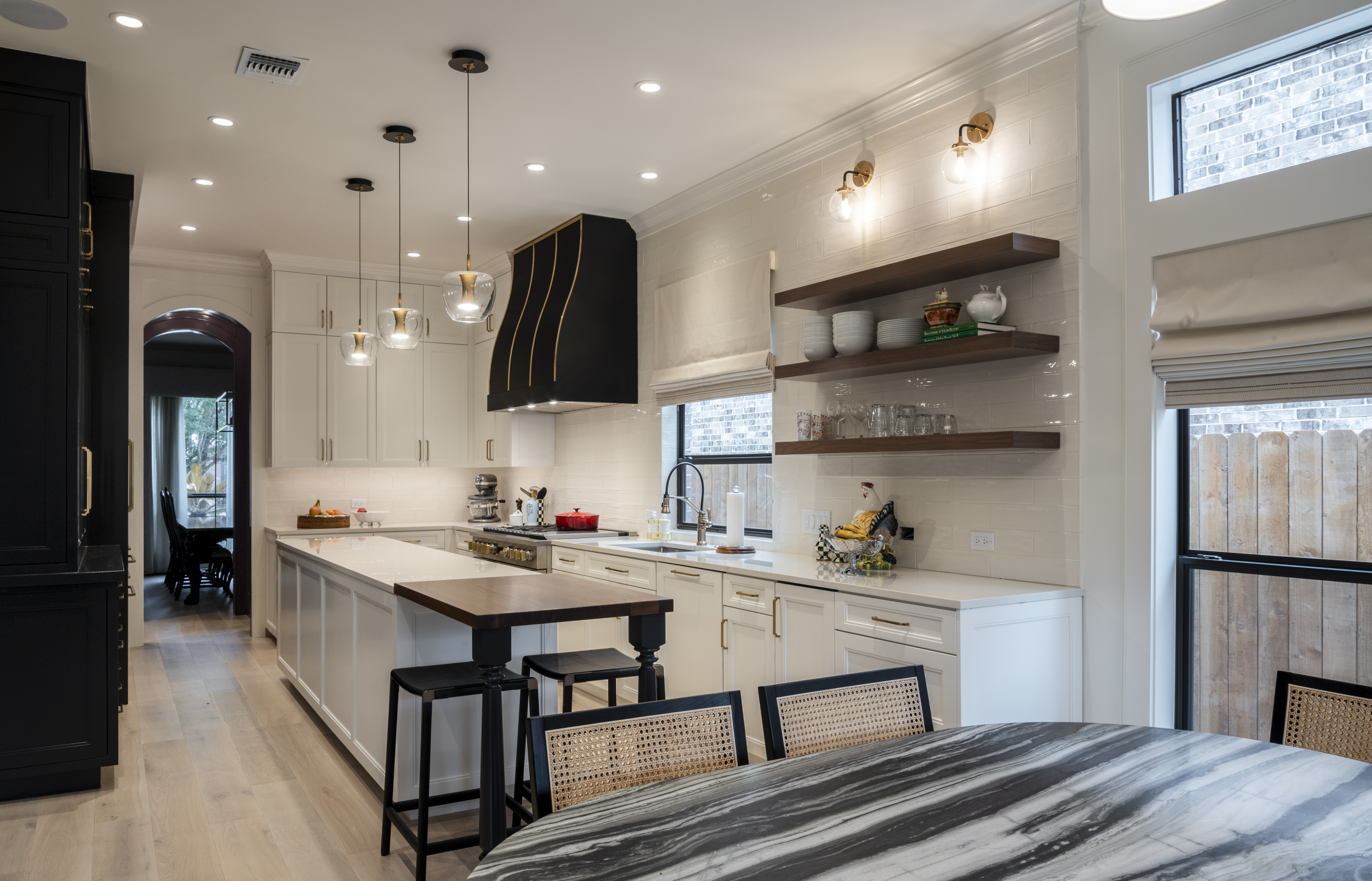 A stunning kitchen design idea featuring a sleek range hood, tuscan-inspired elements, white kitchen cabinets and countertops, beautiful marble backsplash