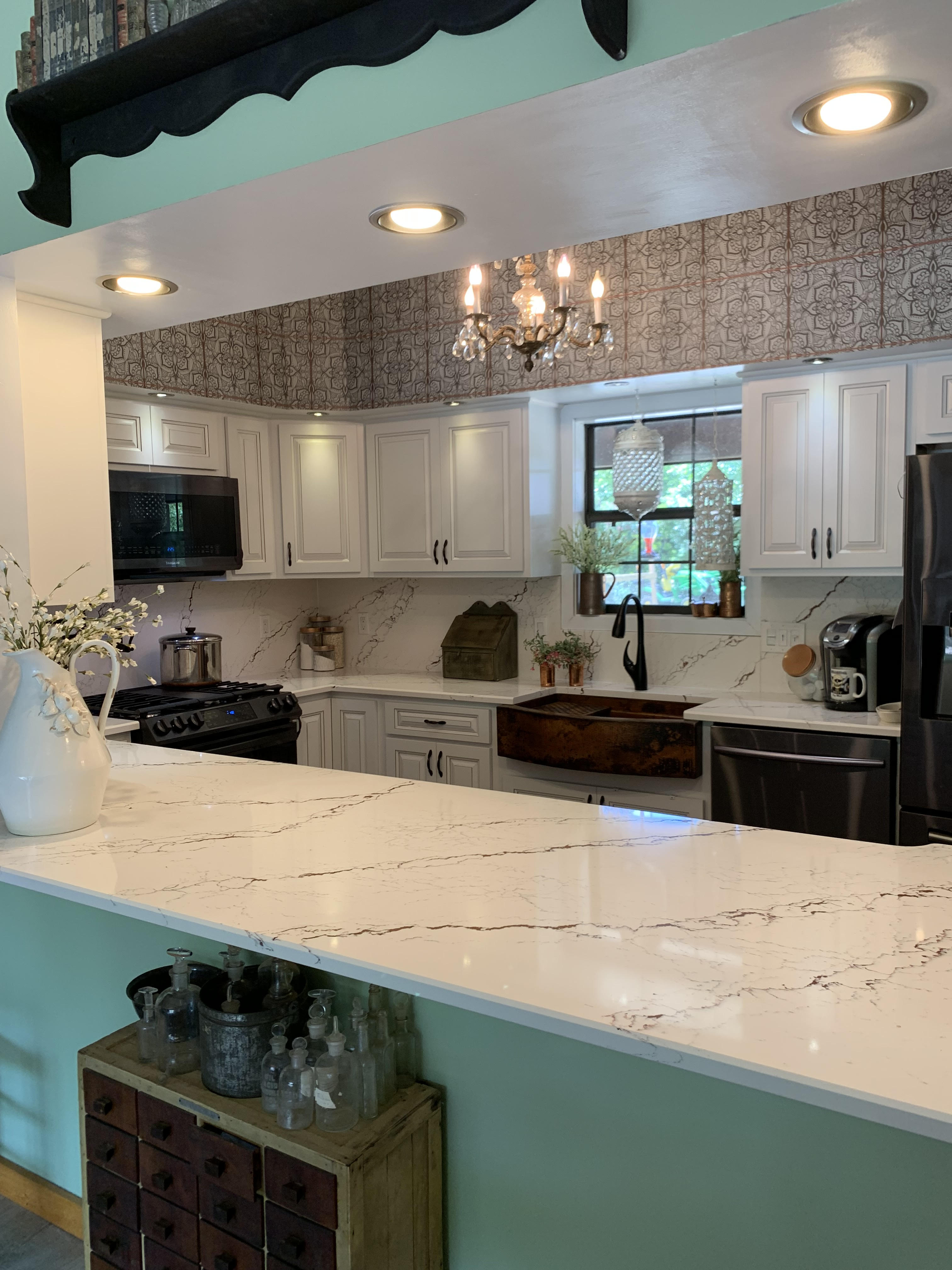 Kitchen design idea featuring a farmhouse sink, country kitchen designs, white kitchen cabinets, white kitchen countertops, stunning marble backsplash