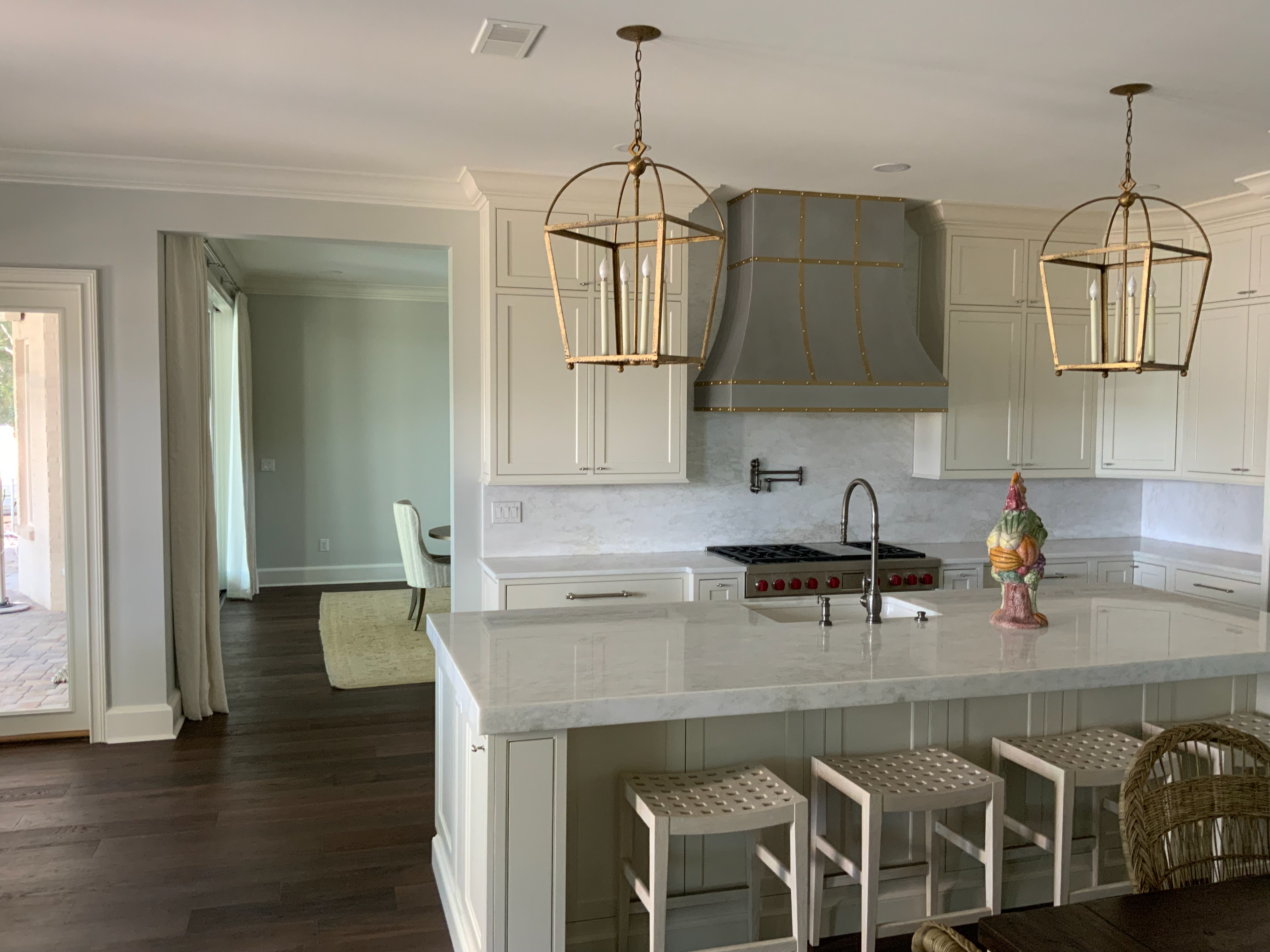 Wondrous traditional kitchen with white cabinets, white countertops, sleek marble backsplash, featuring a captivating range hood