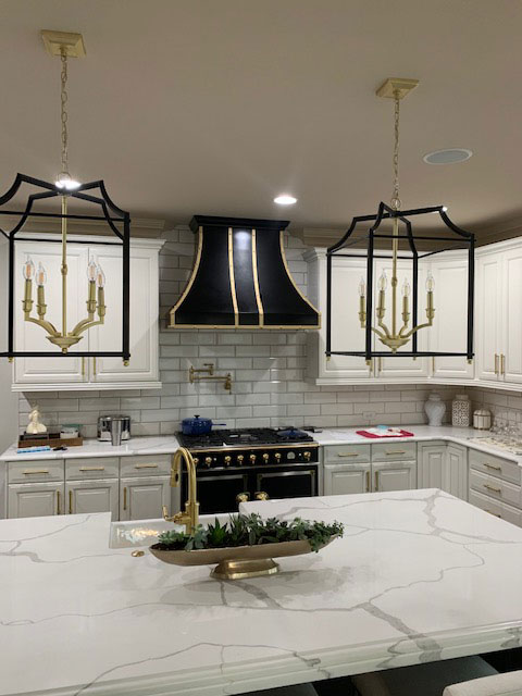 A contemporary kitchen featuring white kitchen cabinets, marble kitchen countertops, stylish brick backsplash is enhanced by a sleek range hood design