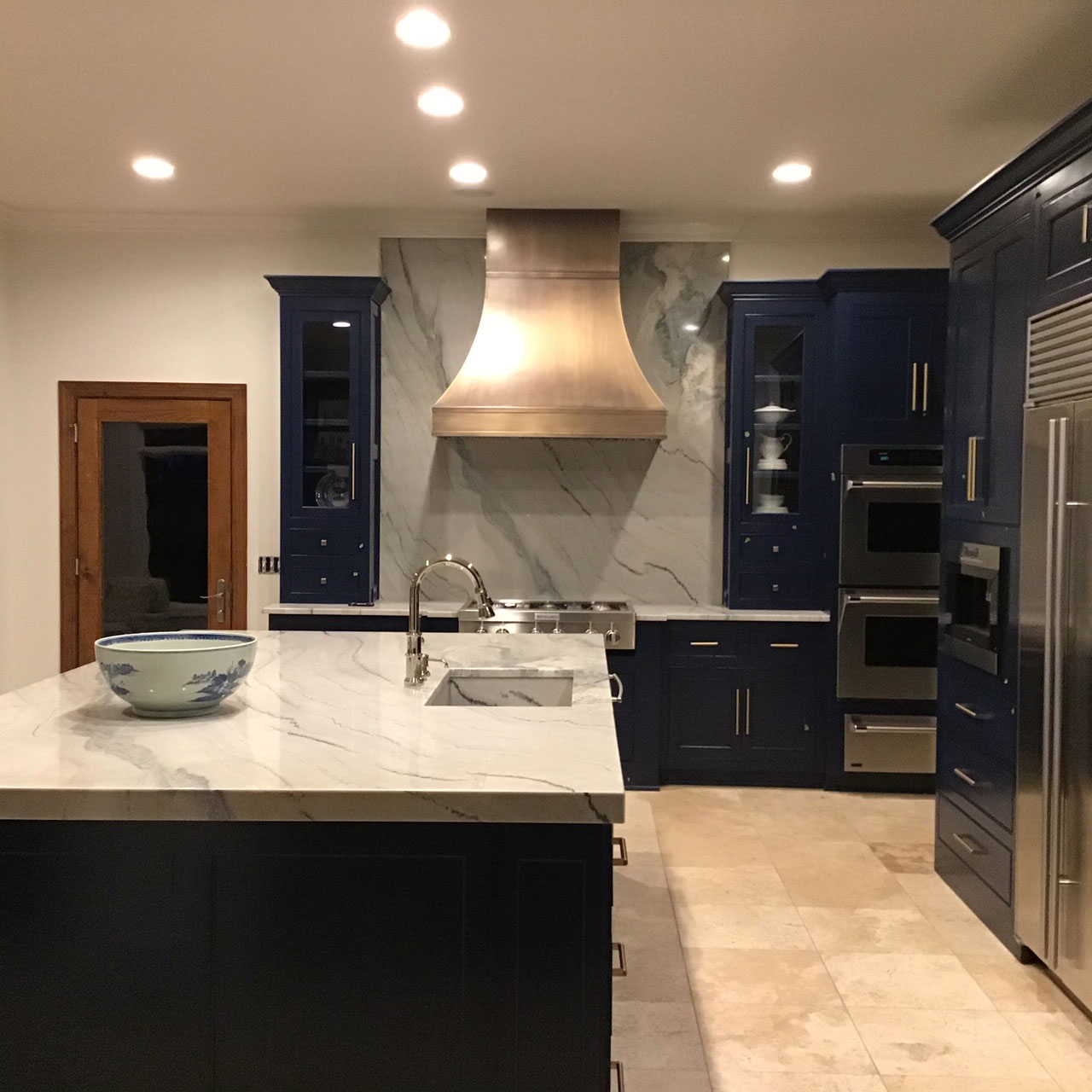French kitchen design with blue kitchen cabinets,elegant marble kitchen countertops captivating marble backsplash, topped off with a range hood