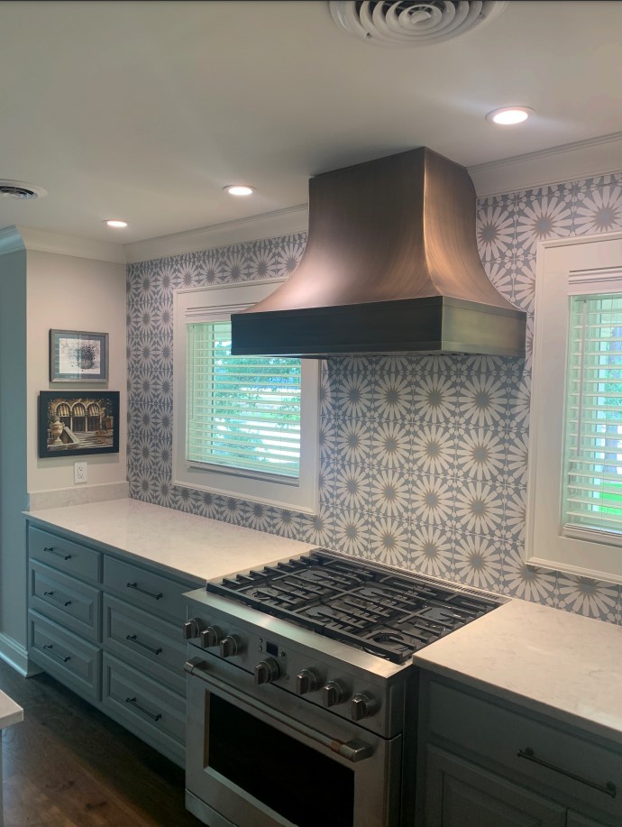 Stunning french kitchen design with white kitchen cabinets, marble countertops, marble backsplash complemented by a stylish range hood