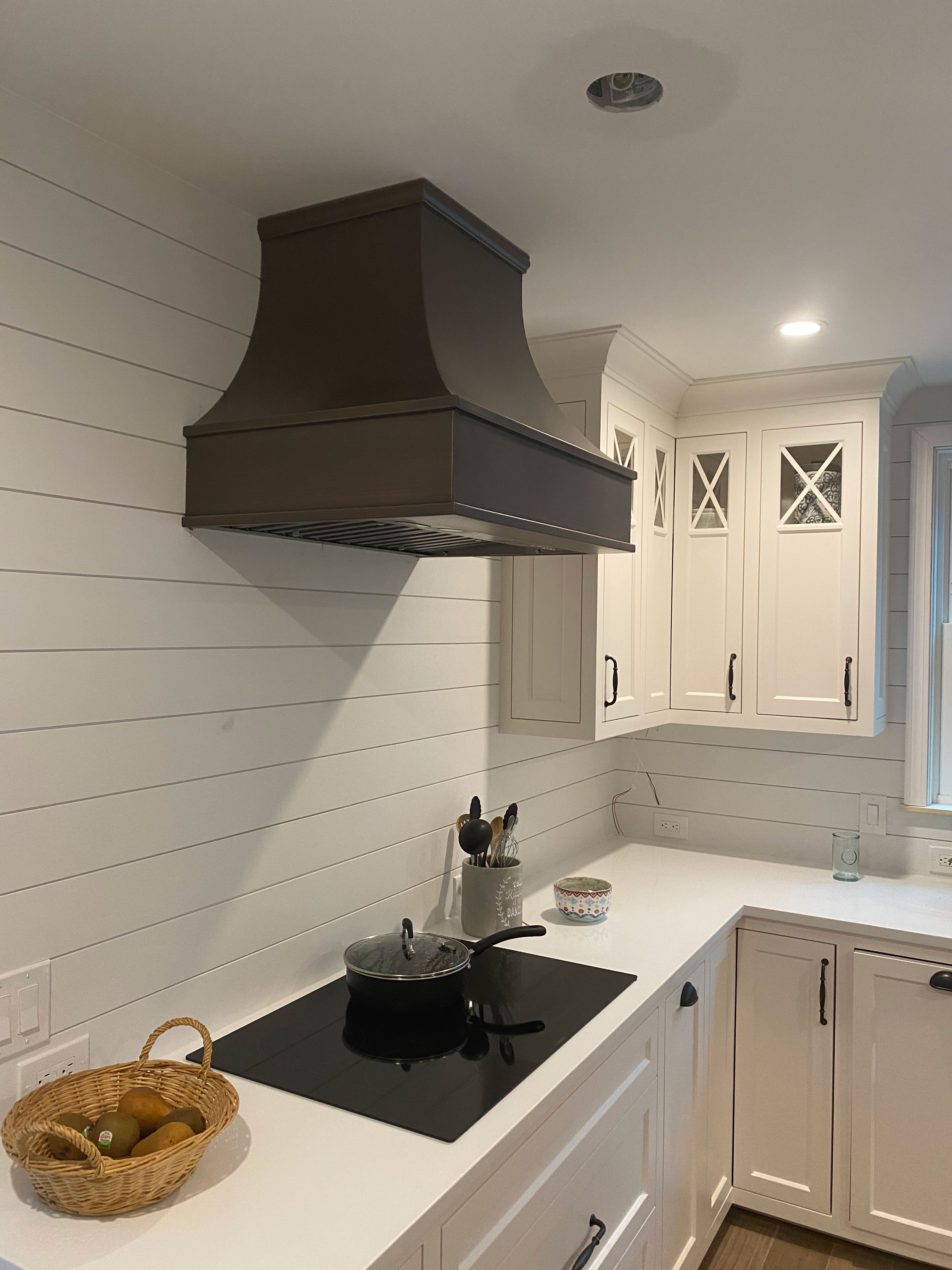 Modern kitchen with white cabinets, countertops, stunning brick backsplash, complemented by a stylish range hood