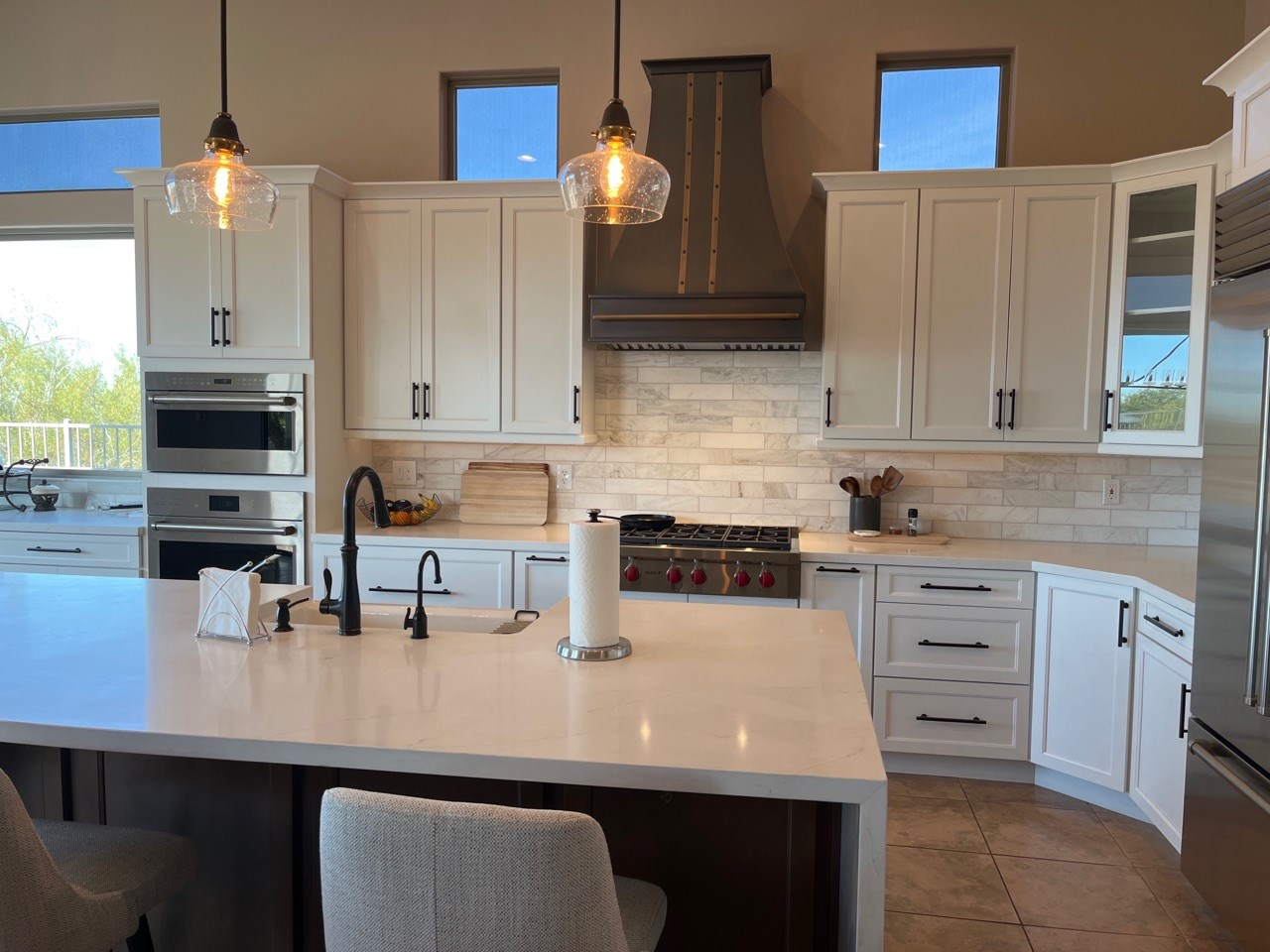 A modern kitchen design with a farmhouse sink, rustic-inspired elements, white kitchen cabinets and countertops, white tile backsplash with range hood