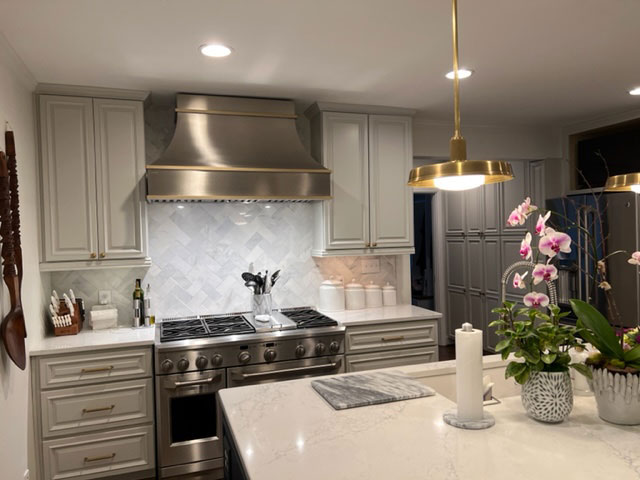 A modern tuscan-inspired kitchen with white cabinets and countertops, featuring a sleek range hood stylish brick backsplash