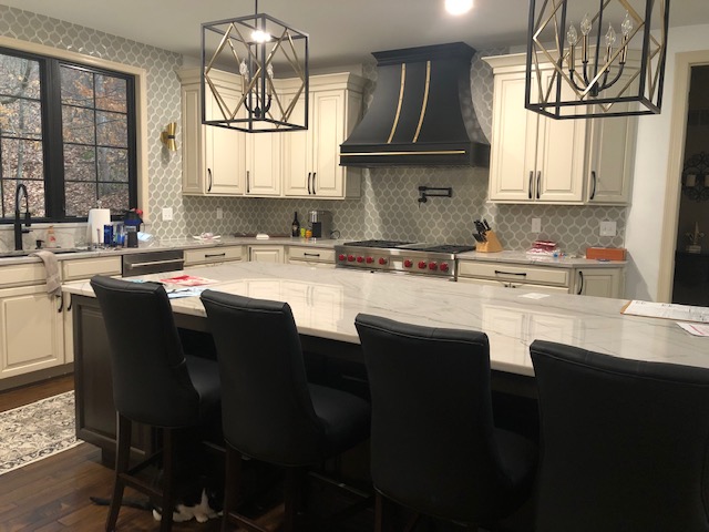 French kitchen design featuring white kitchen cabinets, marble kitchen countertops, captivating copper backsplash, complemented by a sleek range hood