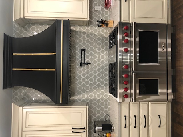 A stunning french kitchen design with white kitchen cabinets, marble kitchen countertops, captivating copper backsplash, complemented by a stylish range hood