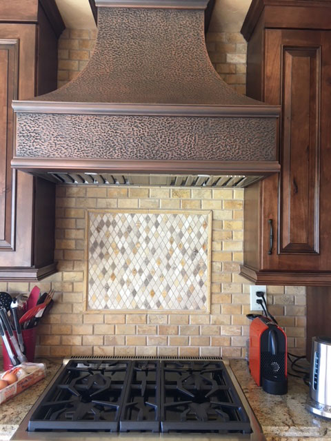Incorporate brown kitchen cabinets with range hood, a sleek marble countertop, complemented by a stylish brick backsplash