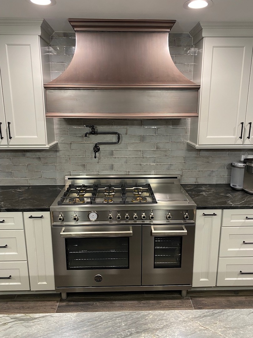 Brushed copper range hood in modern kitchen with gray ceramic brick wall World CopperSmith