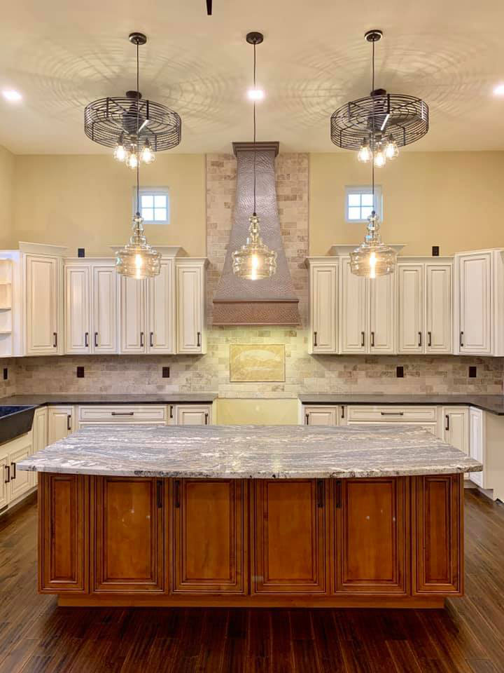 A craftsman kitchen with white kitchen cabinets, marble kitchen countertops, brick backsplash, featuring a copper sleek range hood