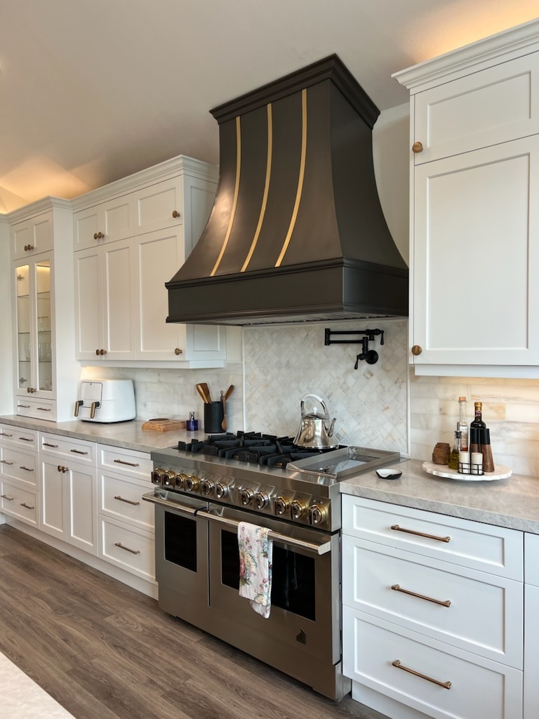 Range hood french kitchen design with white kitchen cabinets, pristine white kitchen countertops, and marble backsplash