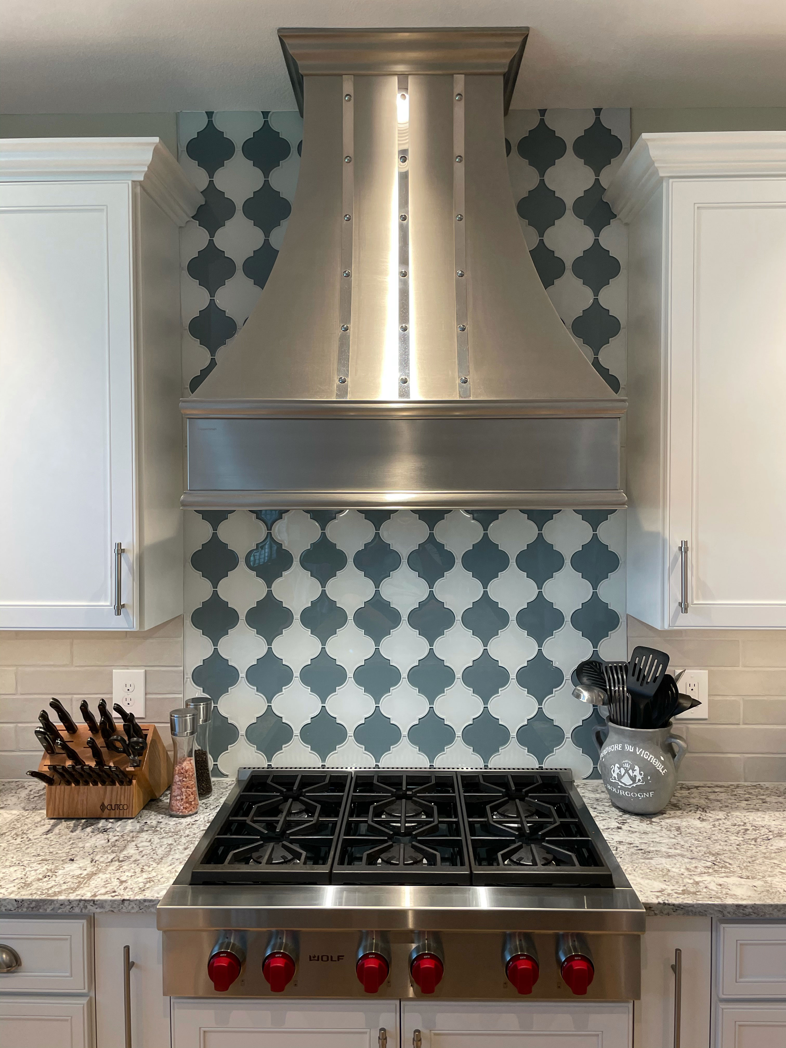 Kitchen design idea featuring range hood, french kitchen design with white kitchen cabinets,marble kitchen countertops and charming brick backsplash