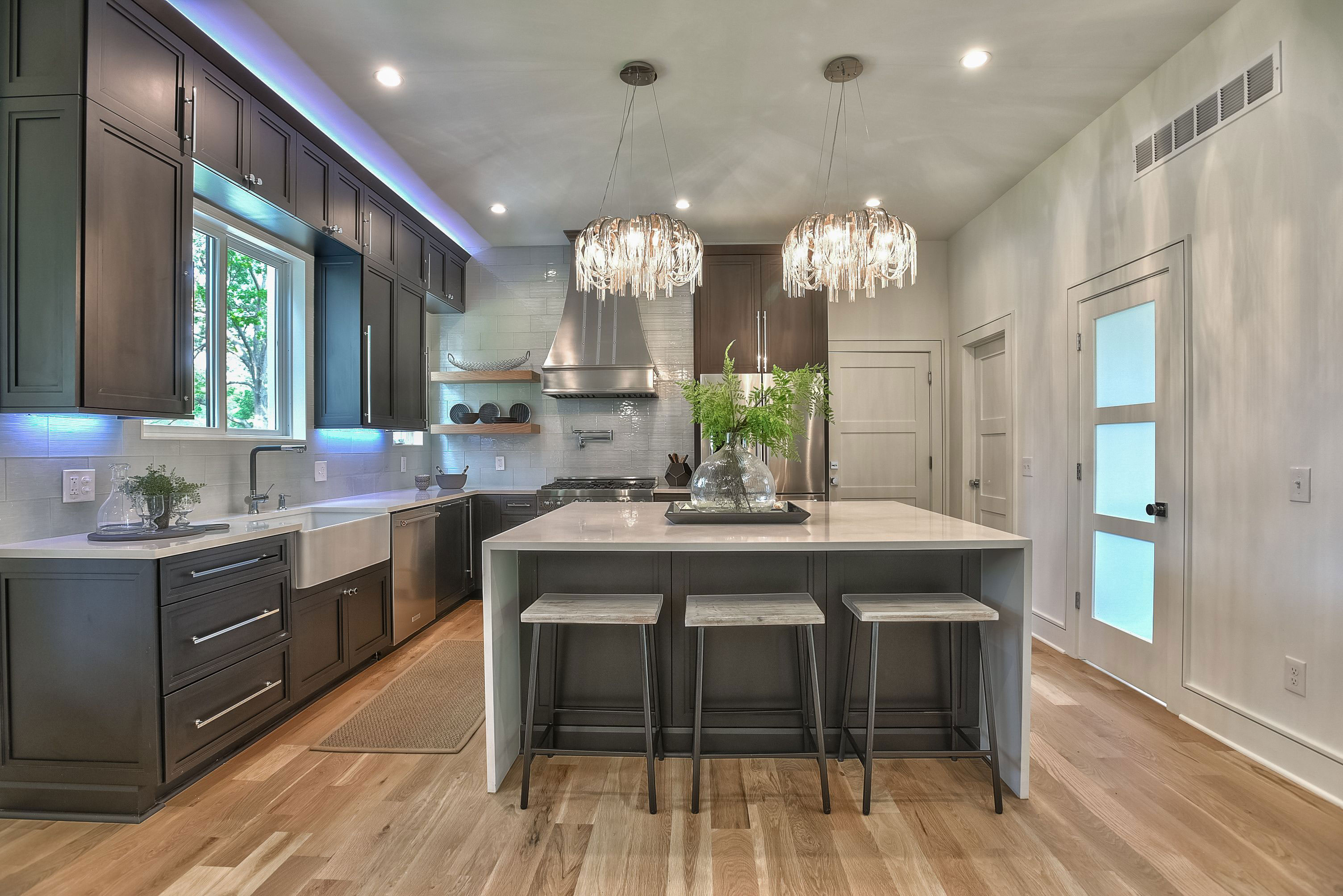 A stylish range hood with a beautiful cottage kitchen with grey kitchen cabinets, white kitchen countertops, stunning brick backsplash