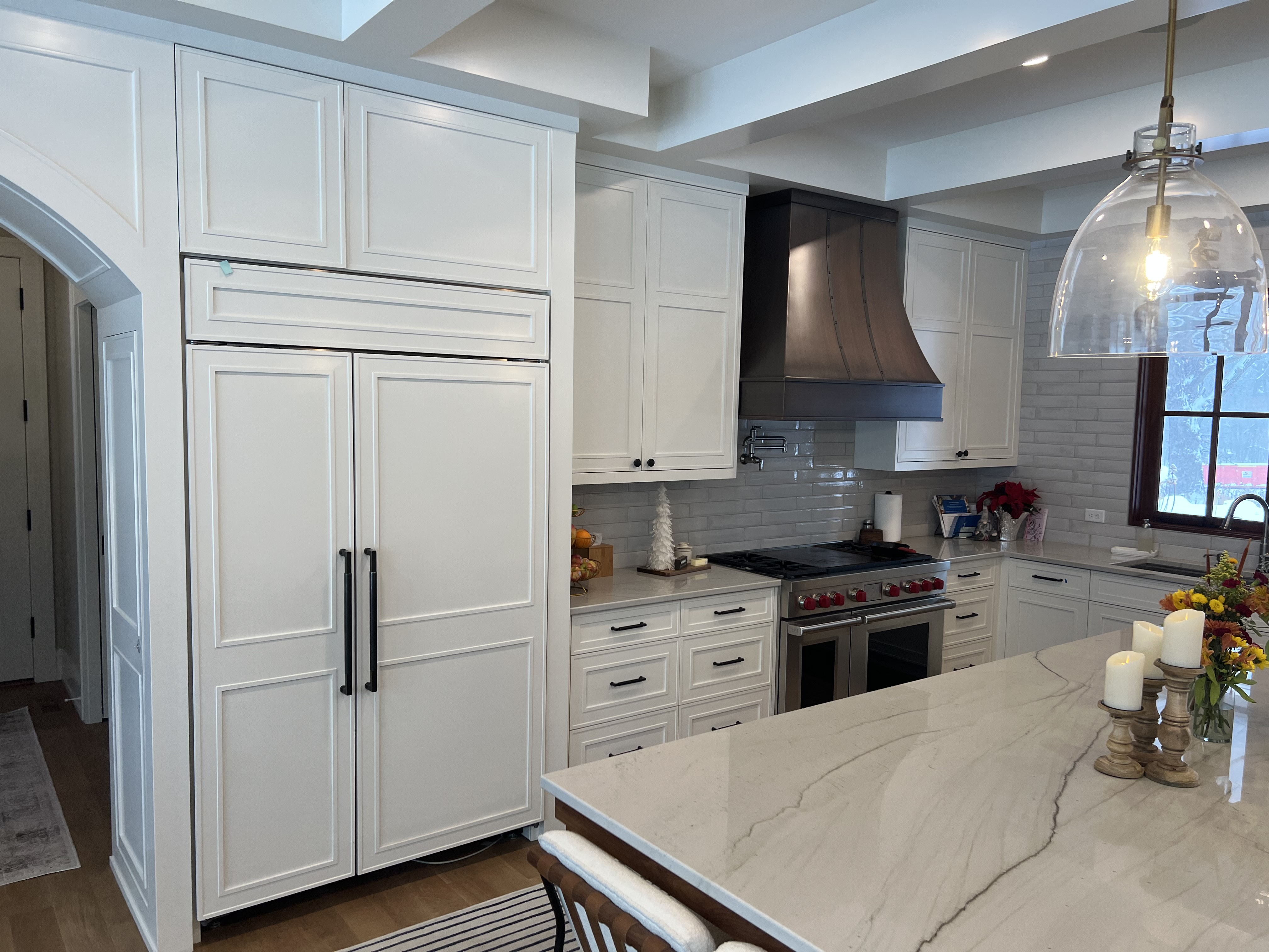 Luxurious marble kitchen countertops, french kitchen design with white kitchen cabinets, stunning white tile backsplash, range hood