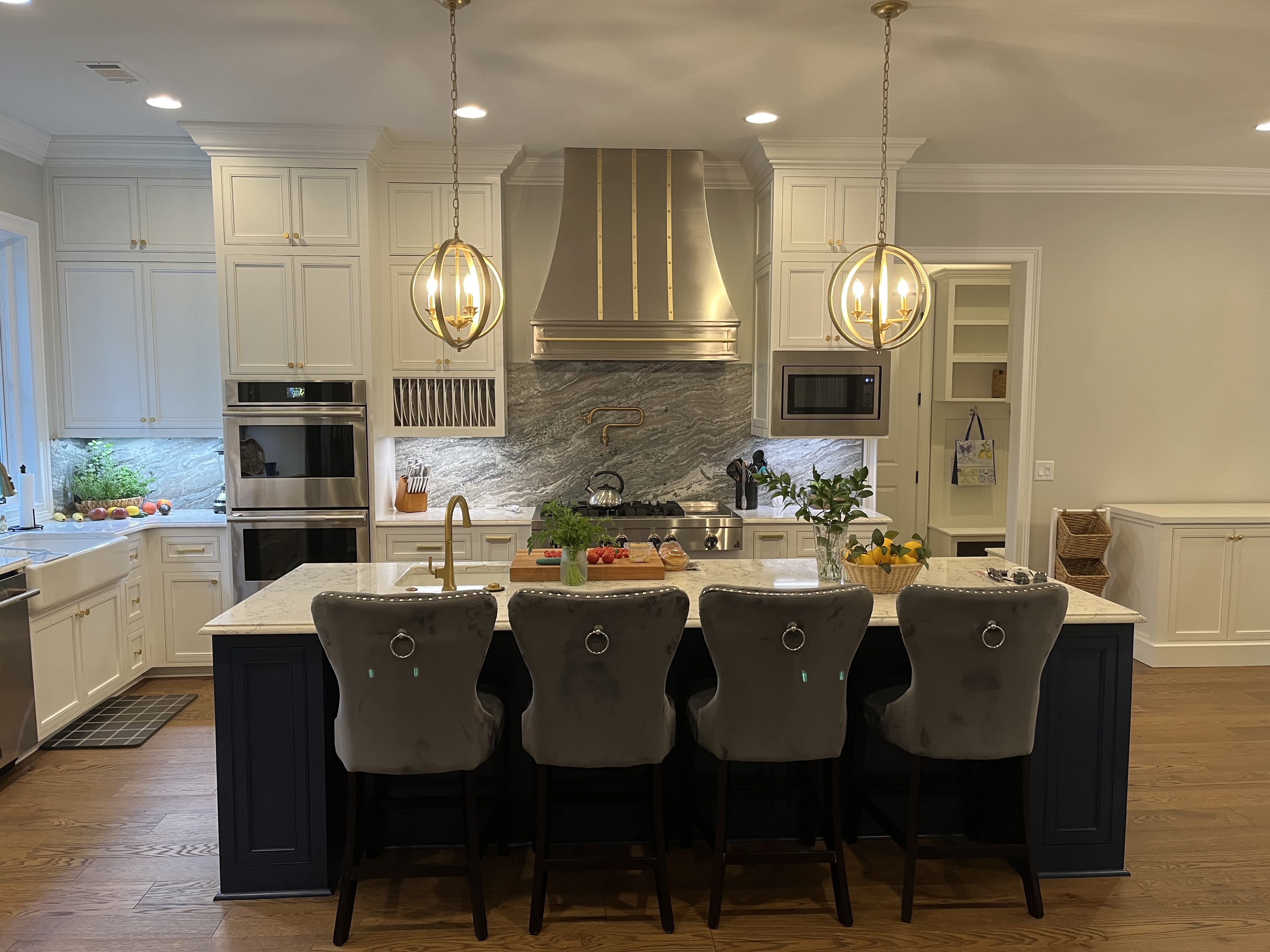 Wonderful kitchen design featuring range hood, white cabinets,marble countertops brick backsplash
