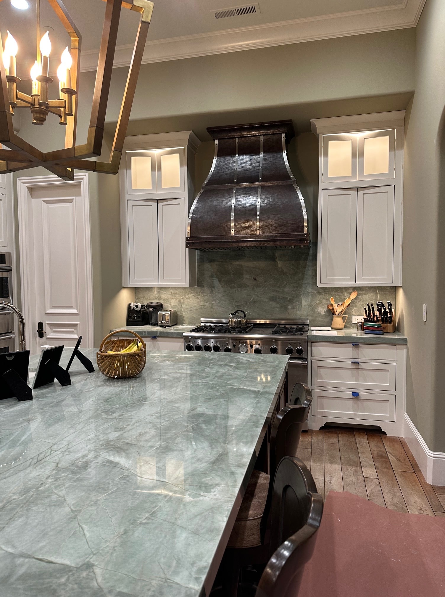 Inspiring range hood and classic kitchen planning, white kitchen cabinets with sleek grey kitchen countertops, and stunning marble backsplash