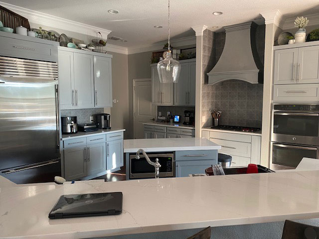 Kitchen with contemporary remodeling idea, range hood, featuring sleek white kitchen cabinets,elegant marble countertops,andstylish brick backsplash