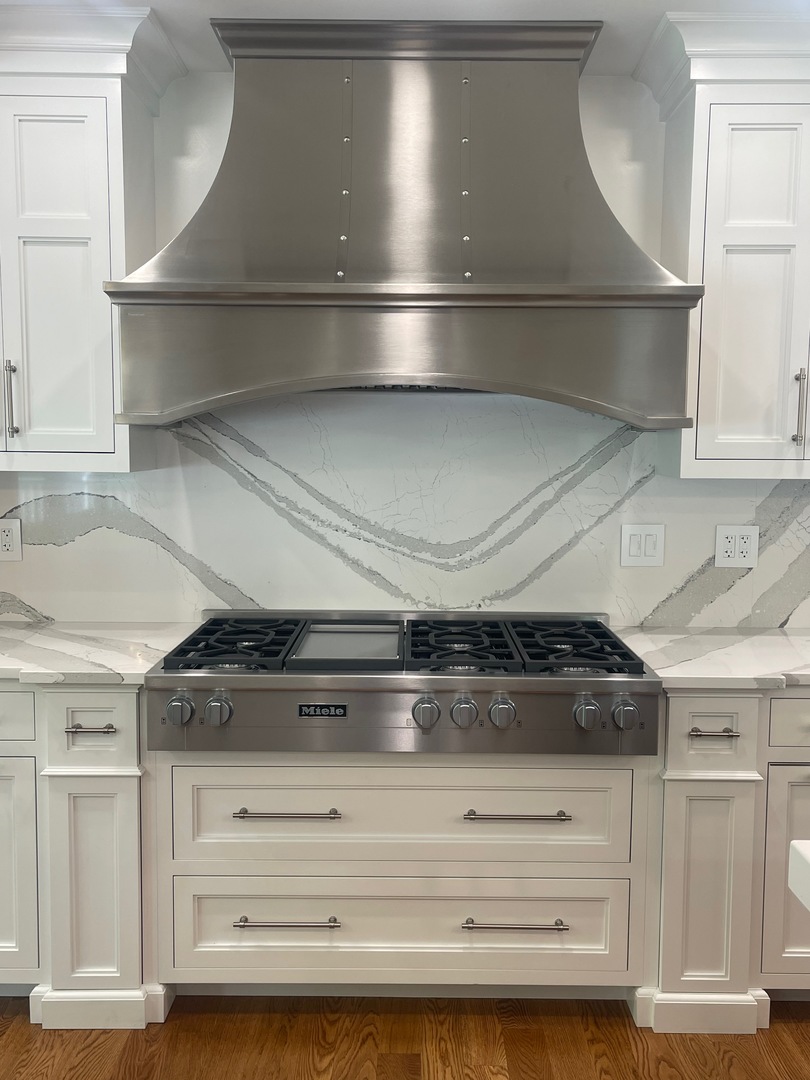 French kitchen design featuring range hood, white cabinets,exquisite marble countertops and marble backsplash