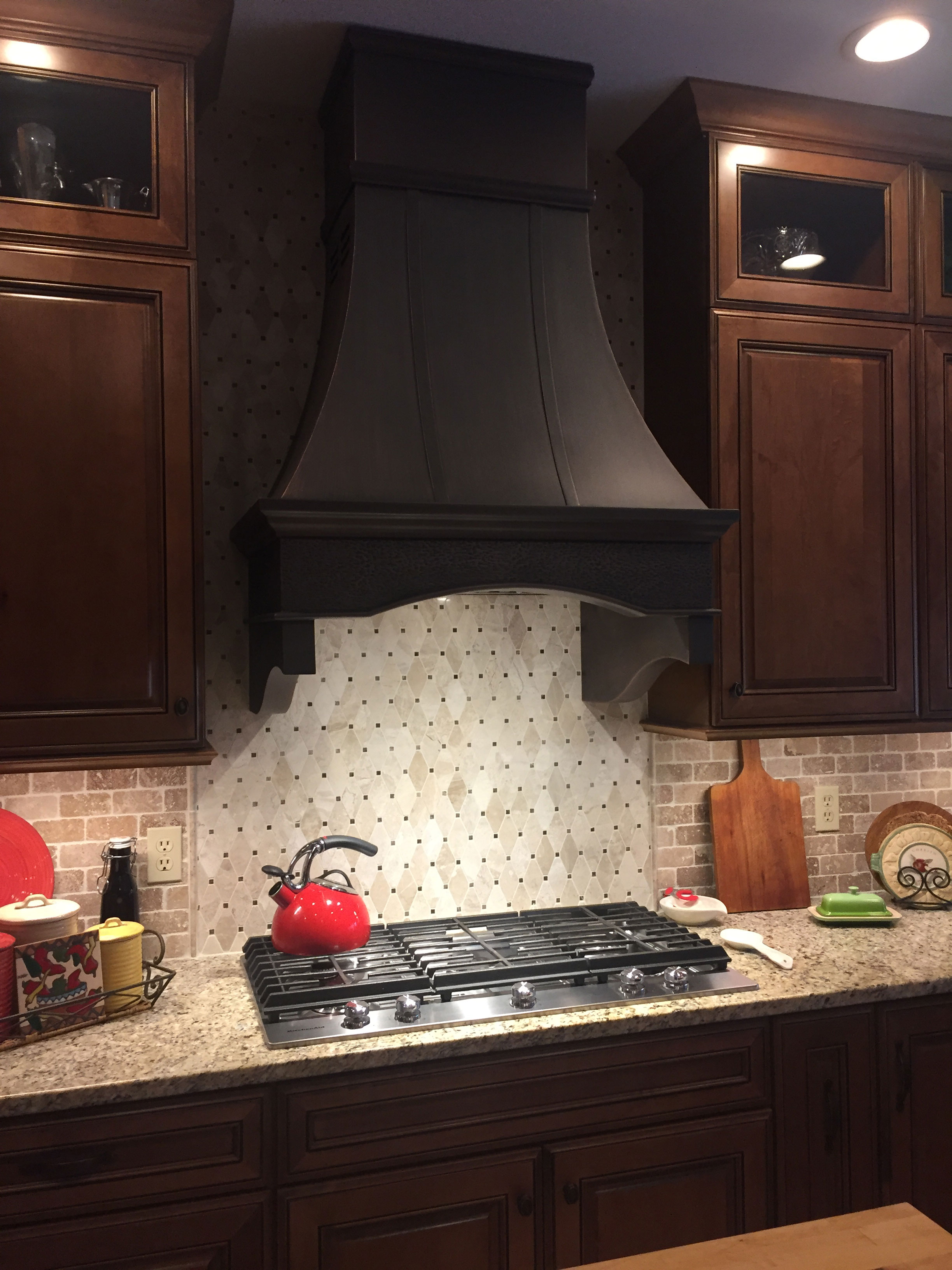 Black range hood in kitchen with tile backsplash World CopperSmith