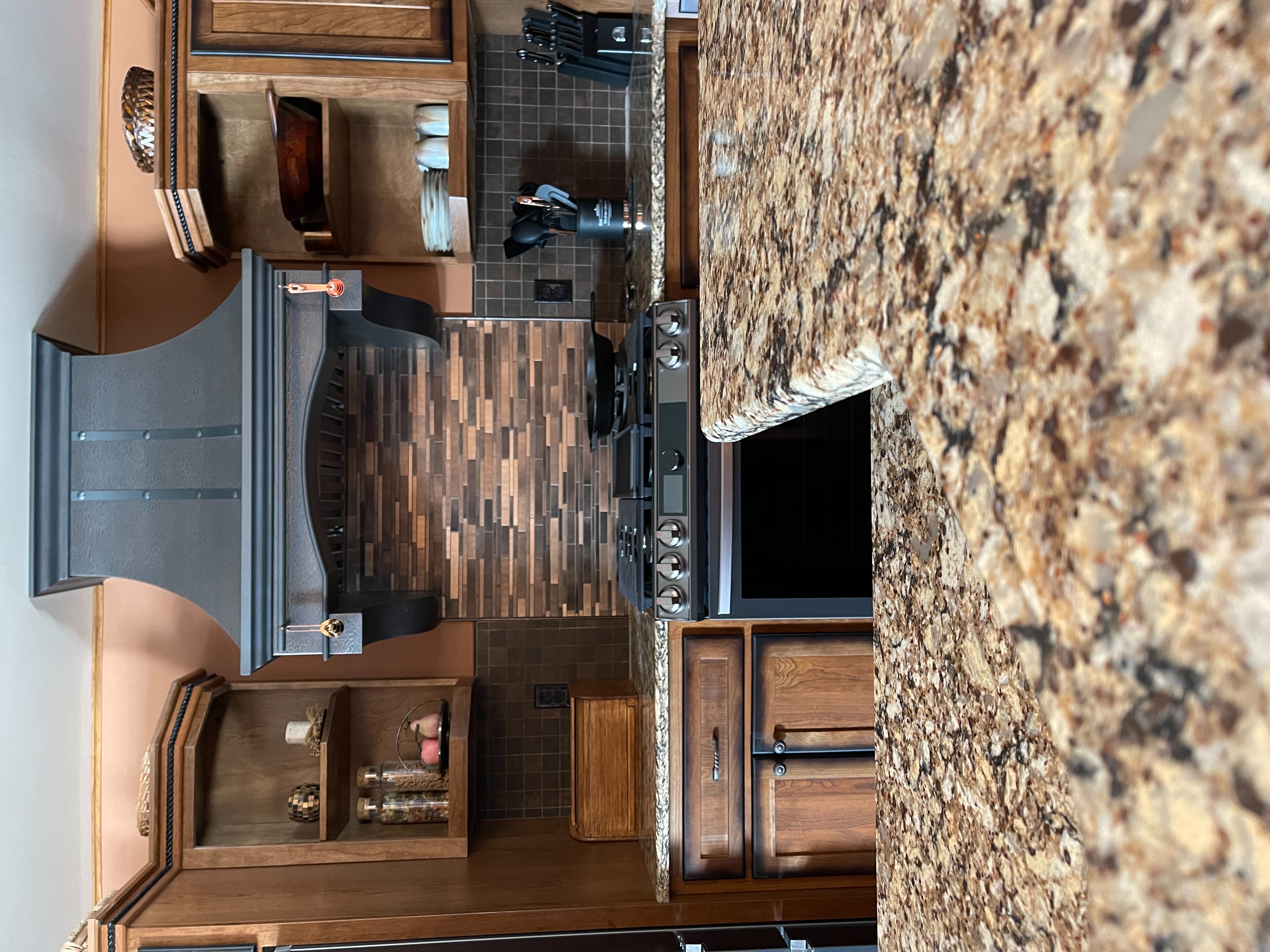 Warmth with rich wood kitchen cabinets and marble kitchen countertops, dazzling copper backsplash, infusing space with a captivating metallic allure