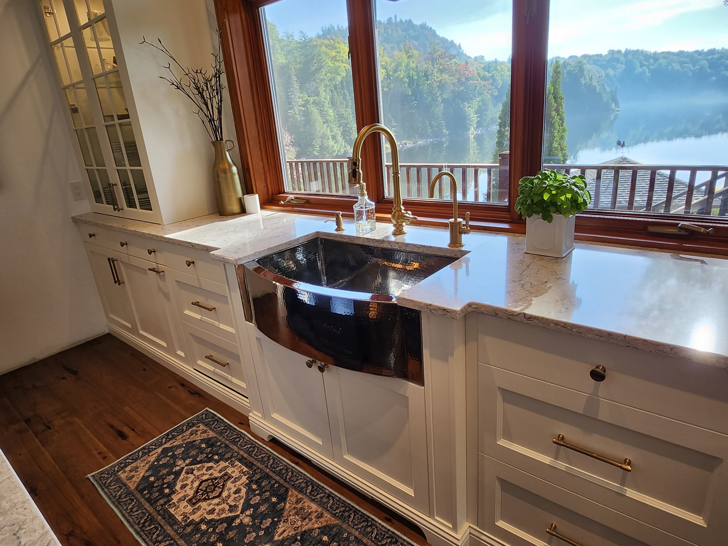 CopperSmith Semi Convex SB Sink Polished Stainless Steel Hand Hammered in a classic style kitchen with marble countertops and white cabinets