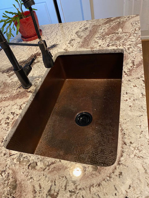 Undermount copper sink with hammered texture with plant on countertop World CopperSmith