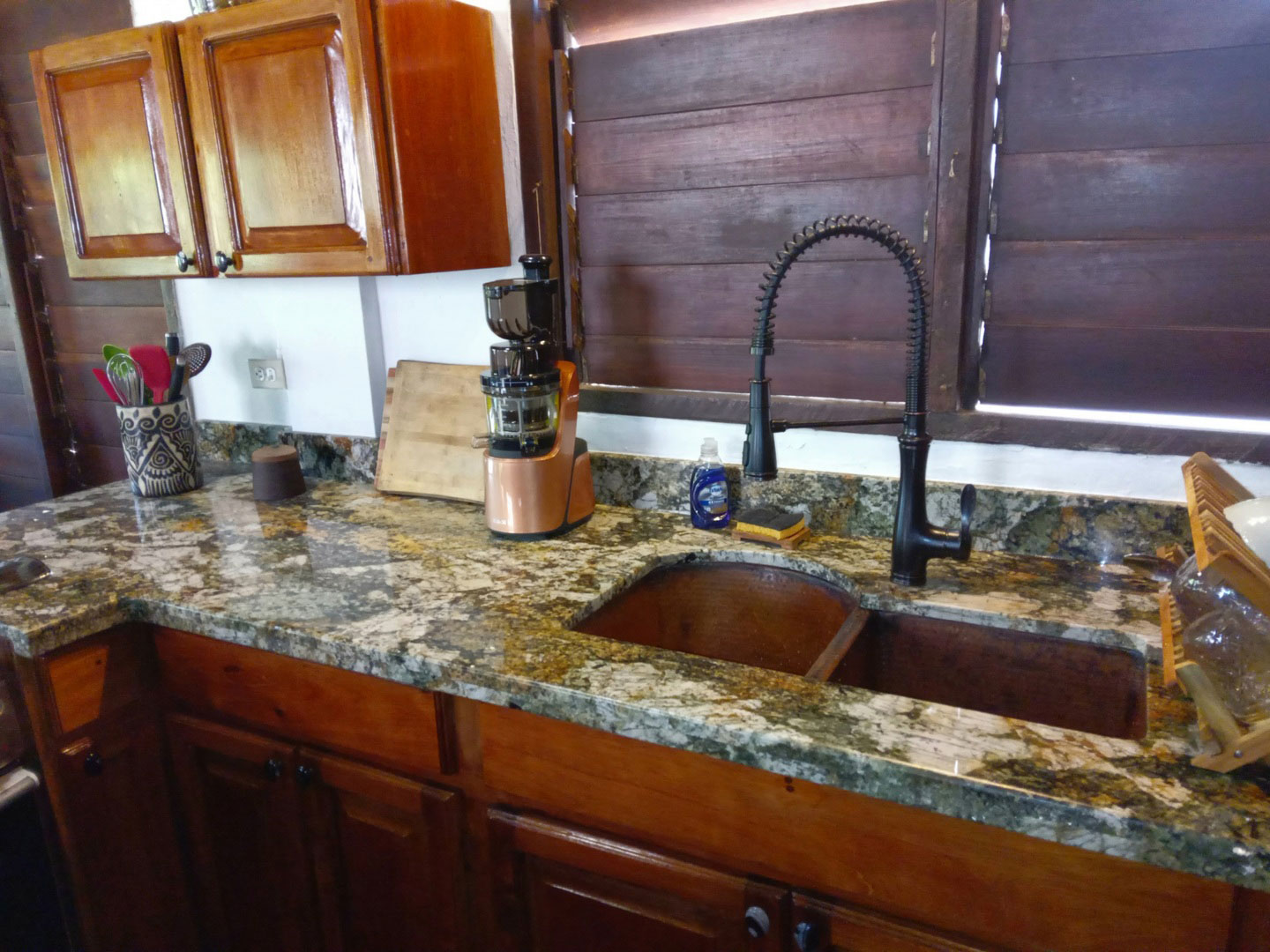 Undermounted copper sink in kitchen with granite countertop and wood shutters World CopperSmith