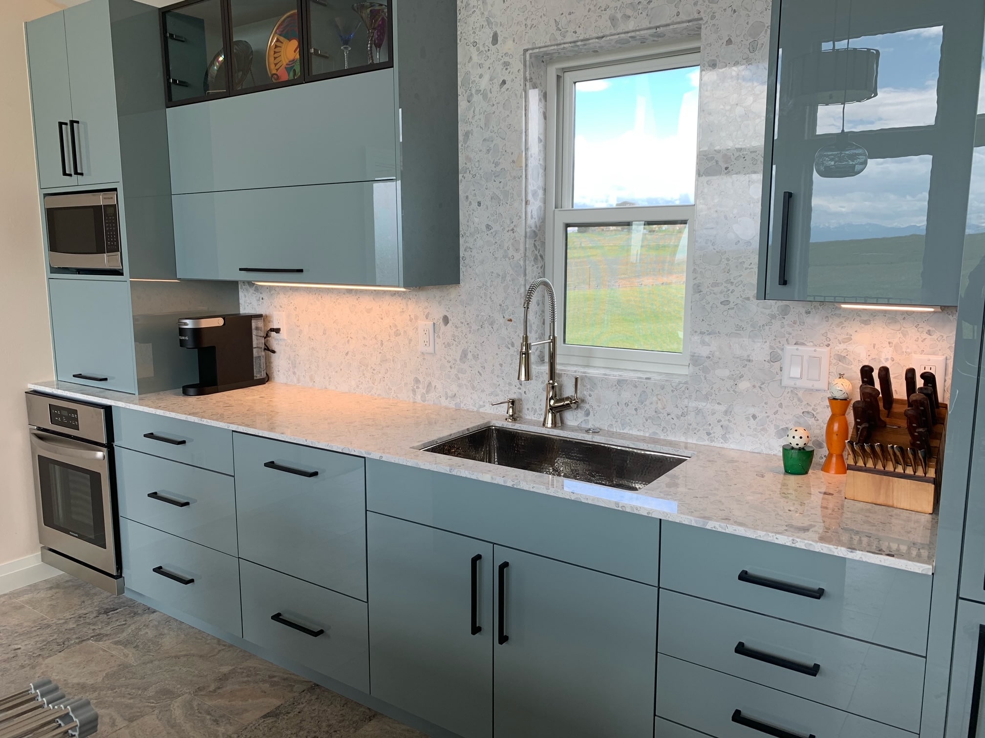 Modern kitchen design idea featuring a farmhouse sink, rustic-inspired decor, gray kitchen cabinets, marble countertops, marble backsplash