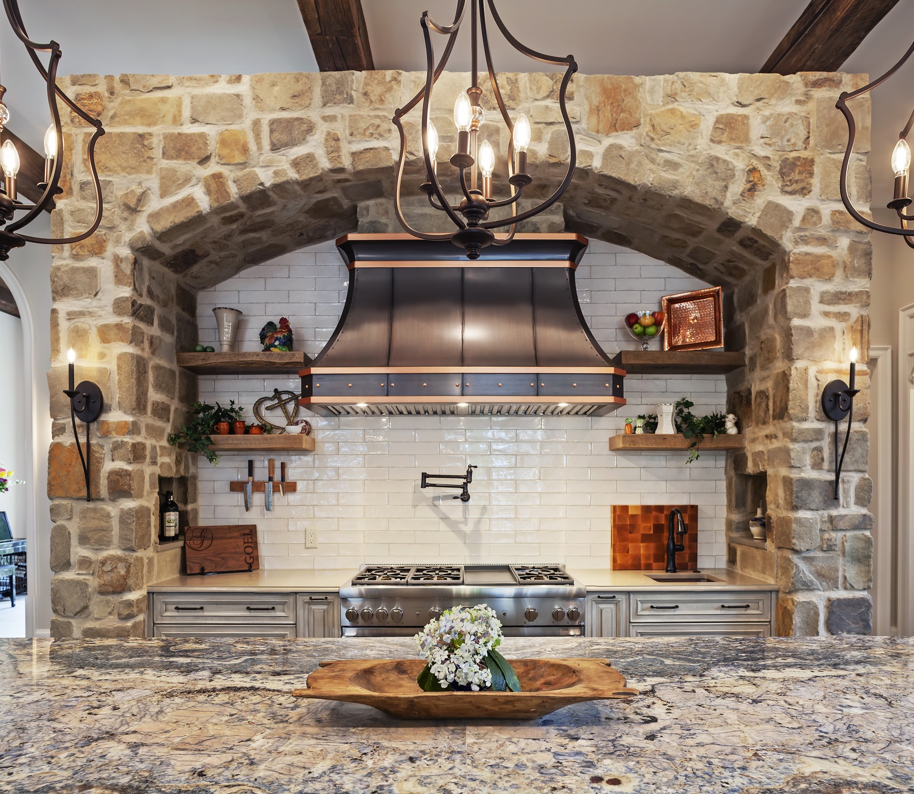 Rustic kitchen design with copper hood, grey cabinets, marble countertops and brick backsplash